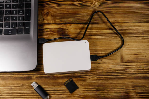 istock External HDD connected to laptop computer, SD memory card and USB flash drive on a wooden desk. Top view. Concept of data storage 1187000802