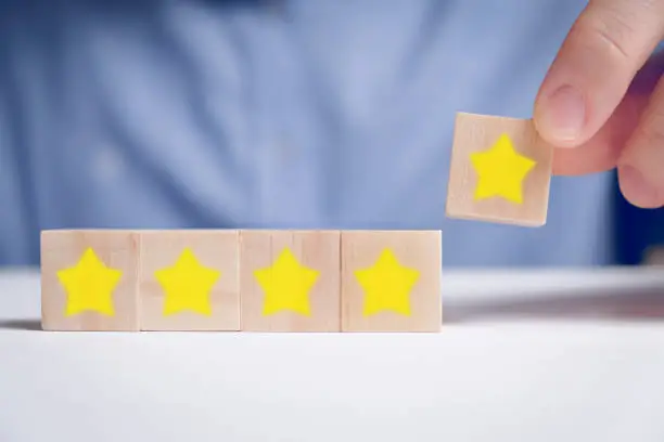 A man in a shirt abstractly rating five stars on wooden cubes. Best score. Close up.