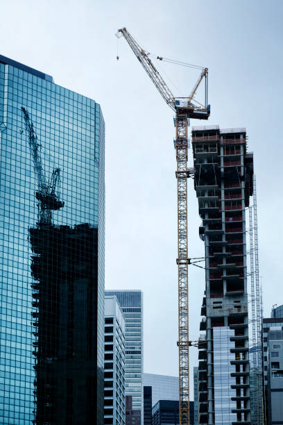 istock construction crane and its reflection on windows of tall office building exterior 1187004485