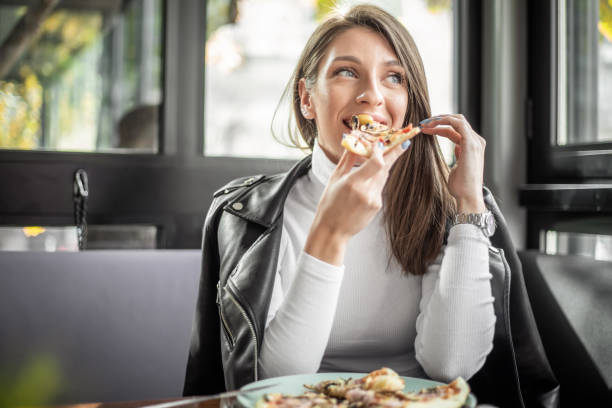 istock Woman eating pizza at restaurant 1187005617