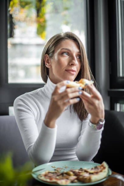 istock Woman eating pizza at restaurant 1187005676