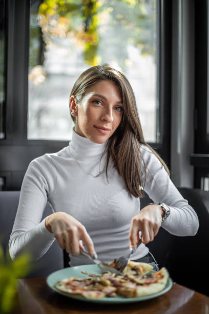 istock Woman eating pizza at restaurant 1187005802