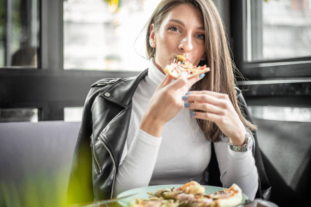 istock Woman eating pizza at restaurant 1187005808