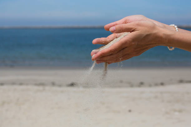 istock Sand pours through fingers against the Sea. 1187005836