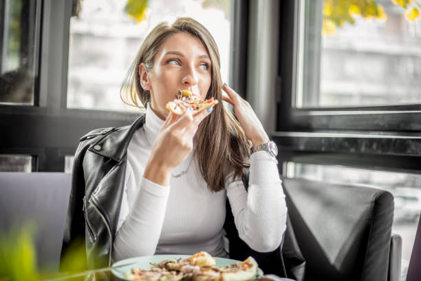 istock Woman eating pizza at restaurant 1187005868
