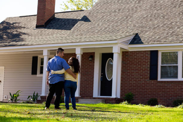 istock Young couple in front of new home hugging 1187013392