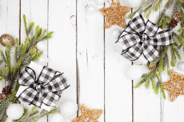 istock Christmas double corner border with branches, ornaments and black and white checked buffalo plaid gifts, above view on a white wood background 1187015289