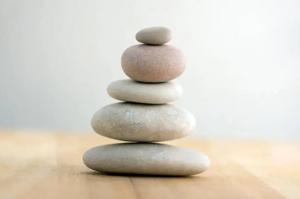 Photo of Stone cairn on striped grey white background, five stones tower, simple poise stones, simplicity harmony and balance, rock zen