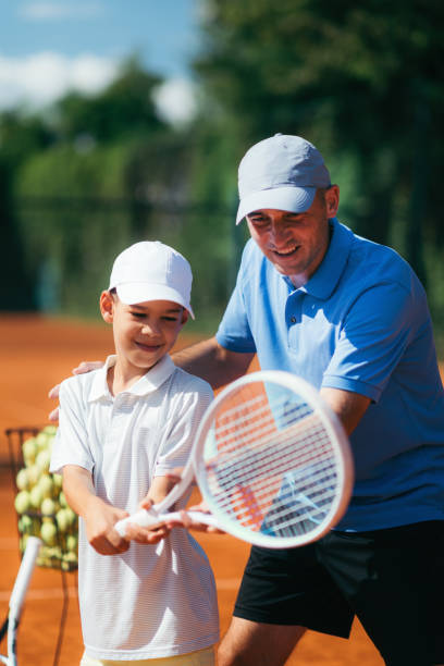 Tennis Lesson. Smiling Coach Explaining Tennis Technique to a Boy Tennis Instructor with Young Talent on Clay Court. Boy having a Tennis Lesson. tennis coach stock pictures, royalty-free photos & images