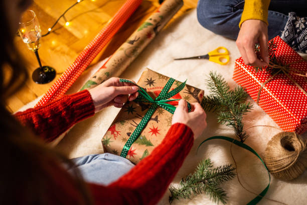 istock Two women wrapping bows on Christmas presents 1187018862