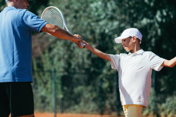 istock Tennis Lesson. Smiling Coach Explaining Tennis Technique to a Boy 1187019414