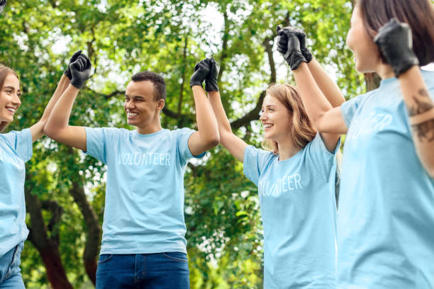 istock Volunteering. Young people volunteers outdoors standing together holding hands smiling successful 1187019764
