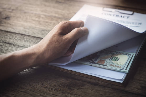istock Compensation, fees, pay, bribery concept, Business man open contract document and look at  dollar simulation money at under document. Contracting for financial gain. 1187020181