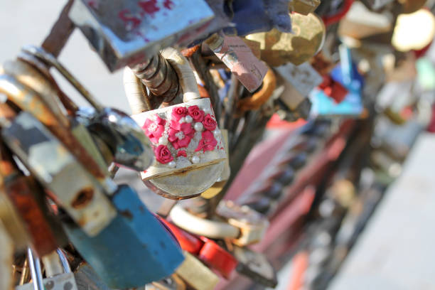 Wedding padlocks chained to the bench in city park. Symbol of love and old wedding tradition. Old rusty sweetheart locks. Horizontal picture of different colorful decorated metal locks with messages