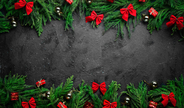 istock Black Christmas Background. Framed by Christmas Tree Branches and Red Decoration Banner. Copy Space 1187025355