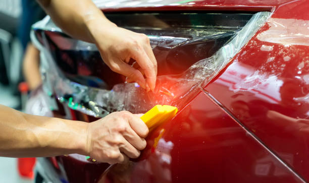 istock Worker install car paint protection film with spatula 1187026188