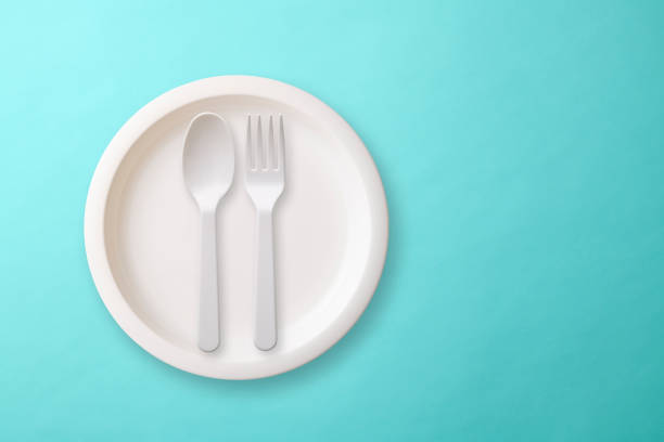 istock White plastic plate with Folk and spoon on light blue background 1187037755