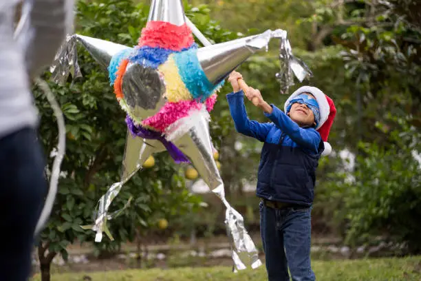 Latin kid hitting a piñata on Christmas in Mexico