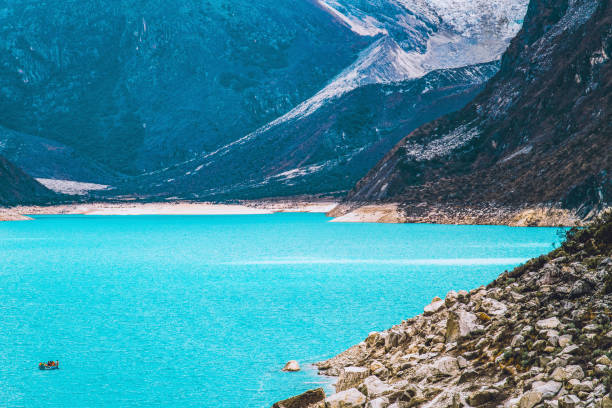 Aerial view of the Andes Mountains Cordillera Blanca in Huaraz, Ancash, Peru, where a turquoise colored glacier lake, Lake Paron, is surrounded by snowcapped high mountain peaks.