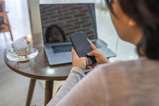 istock Woman using smartphone while sitting in front of laptop 1187056974