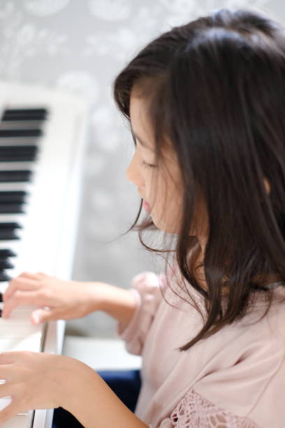 istock Little girl playing the piano 1187064729