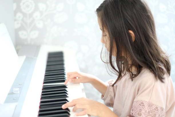 istock Little girl playing the piano 1187064730