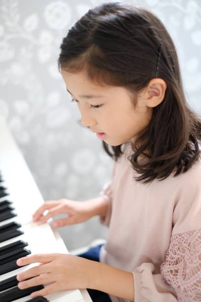 istock Little girl playing the piano 1187064741