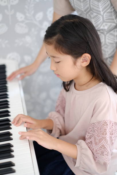 istock Little girl playing the piano 1187064743
