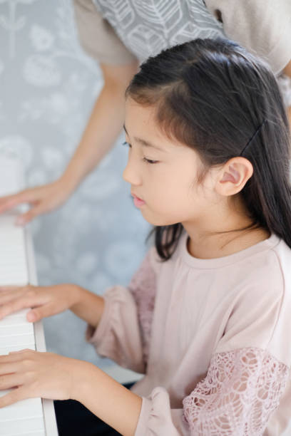 istock Little girl playing the piano 1187064751