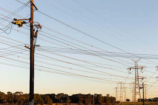 Power line connecting interstate power pylons during golden hour.
