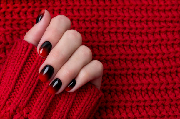 istock Female hand with red black ombre gradient nails in sweater 1187077681