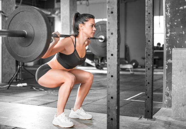 Side view of a woman in the gym. Hard training. Squat. stock photo