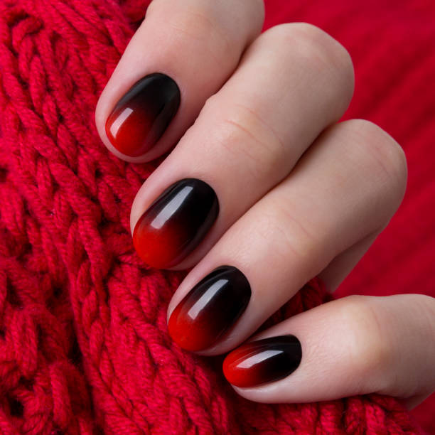 istock Female hand with red black ombre gradient nails hold wool textile fabric 1187077693