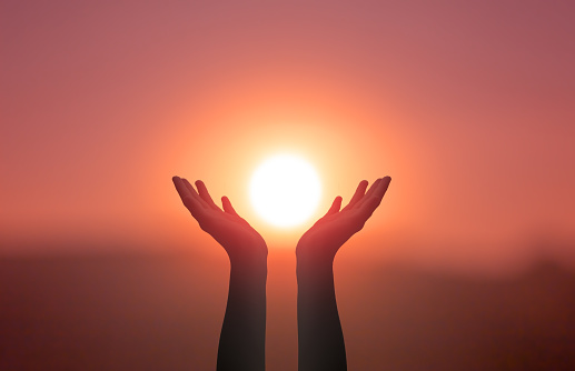 Concepto del Día Internacional del Yoga: Manos levantadas atrapando el sol en el cielo del atardecer photo