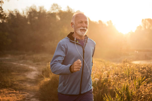 Mature man jogging in by lake in morning time ,feeling young again Senior Caucasian man jogging in a park one senior man only stock pictures, royalty-free photos & images