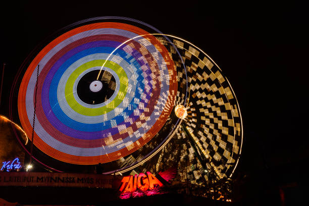 l'evento carnival of light al parco divertimenti linnanmaki. guida la ruota panoramica rinkeli e kehra in movimento, illuminazione notturna, lunga esposizione. - ferris wheel wheel blurred motion amusement park foto e immagini stock