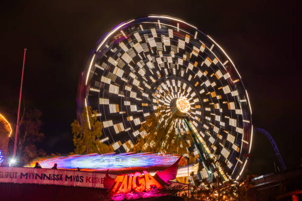 l'evento carnival of light al parco divertimenti linnanmaki. guida la ruota panoramica rinkeli e kehra in movimento, illuminazione notturna, lunga esposizione. - ferris wheel wheel blurred motion amusement park foto e immagini stock