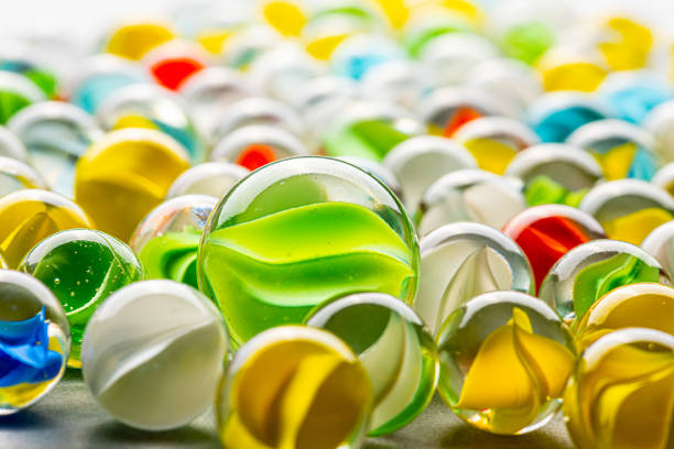 Yellow, green, blue and red glass marbles on a table.
