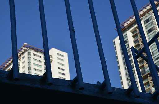 apartment buildings behind metal fence on blue sky