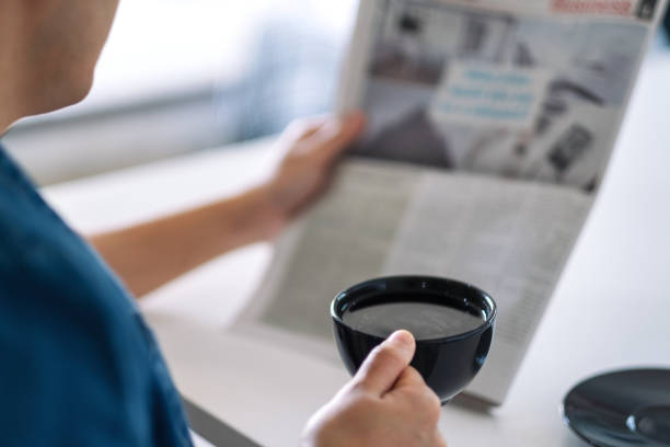 istock a man reading newspaper and drinking coffee in the morning 1187100373