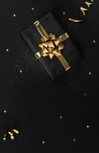 istock Gift box with decorations gold confetti on black background for christmas and new year concept. copy space 1187109617