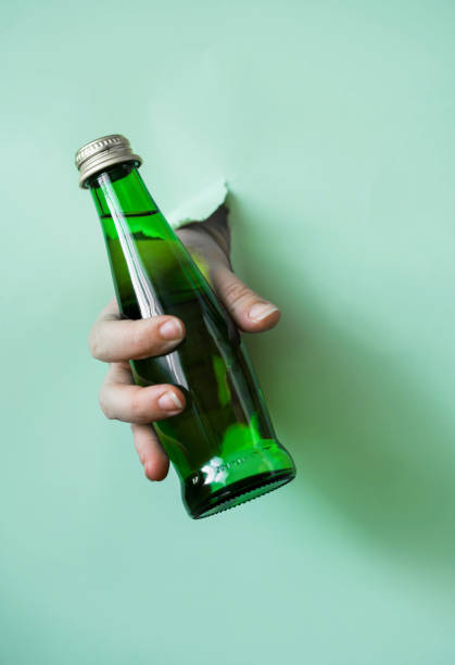 istock A hand holds a green water bottle from a torn paper hole. 1187112601