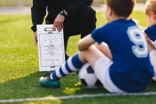 reunión del equipo de fútbol. entrenador dando consejos tácticos usando la tabla blanca de fútbol. coaching youth sports team - soccer child coach childhood fotografías e imágenes de stock