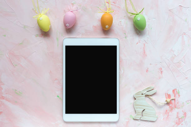 istock Multicolored eggs decoration and tablet on a pink background. Easter concept. 1187113250