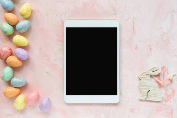 Multicolored eggs decoration and tablet on a pink background. Easter concept.