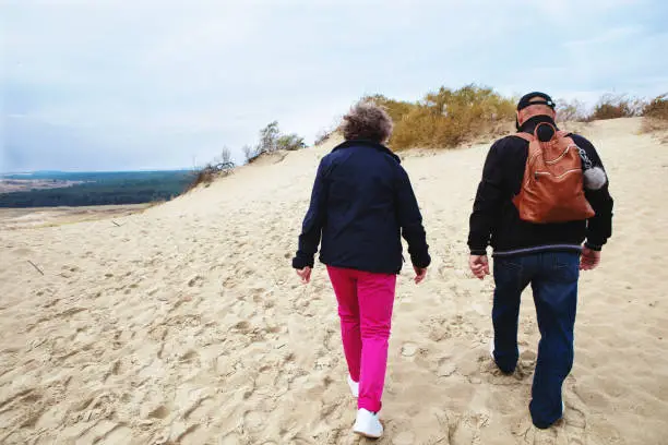 Nida, Lithuania - Sept 8, 2019: married man and woman - senior couple - live a healthy lifestyle and have a walk on the dunes of the Baltic sea.