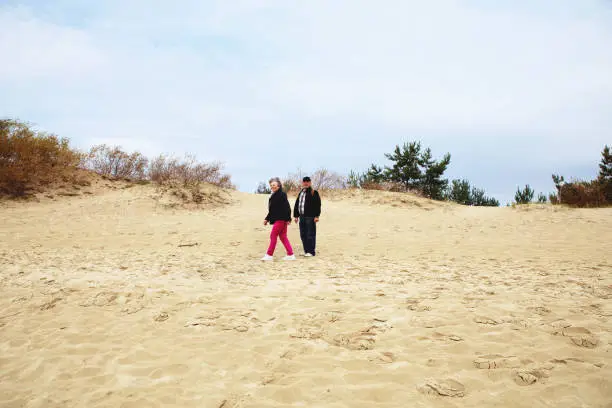 Nida, Lithuania - Sept 8, 2019: married man and woman - senior couple - live a healthy lifestyle and have a walk on the dunes of the Baltic sea.