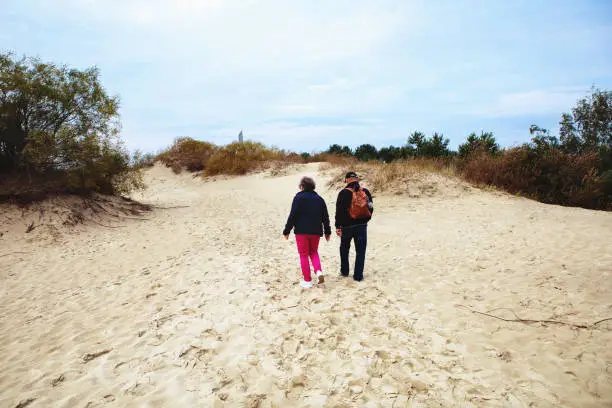 Nida, Lithuania - Sept 8, 2019: married man and woman - senior couple - live a healthy lifestyle and have a walk on the dunes of the Baltic sea.