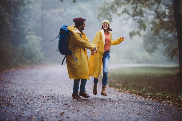 istock Happy couple in raincoats having fun in misty forest. 1187114989