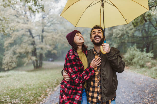 istock Cheerful embraced couple taking a walk on a rainy day at forest. 1187115116